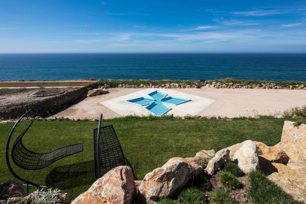 a park with a beach and a bench and some rocks at Chalet O Amorzinho Sintra Praia in Sintra