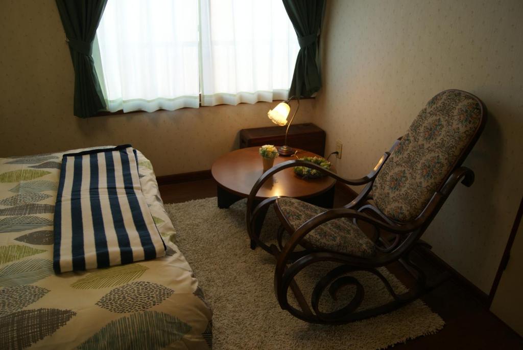 恵庭市にあるIZARI Villageのベッドルーム1室(ベッド1台、椅子、テーブル付)