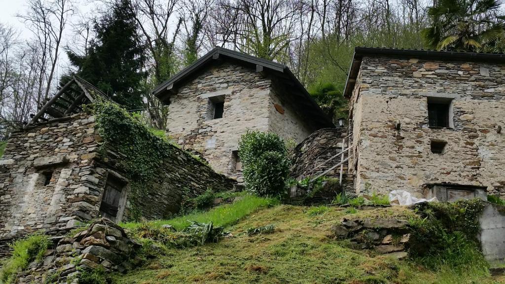 two stone buildings sitting on top of a hill at Casa Accogliente Valle Cannobina in Le Biuse