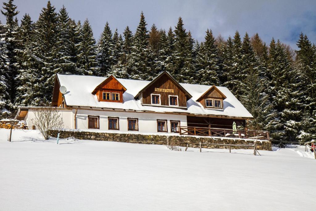 a house covered in snow in front of trees at Horský Ranč in Pec pod Sněžkou