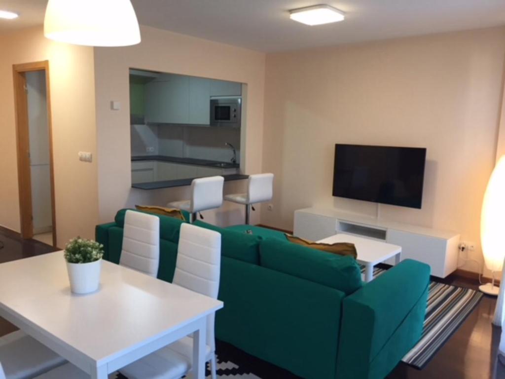 フィニステレにあるApartamentos Finisterre Atlánticoのリビングルーム(緑のソファ、テーブル付)