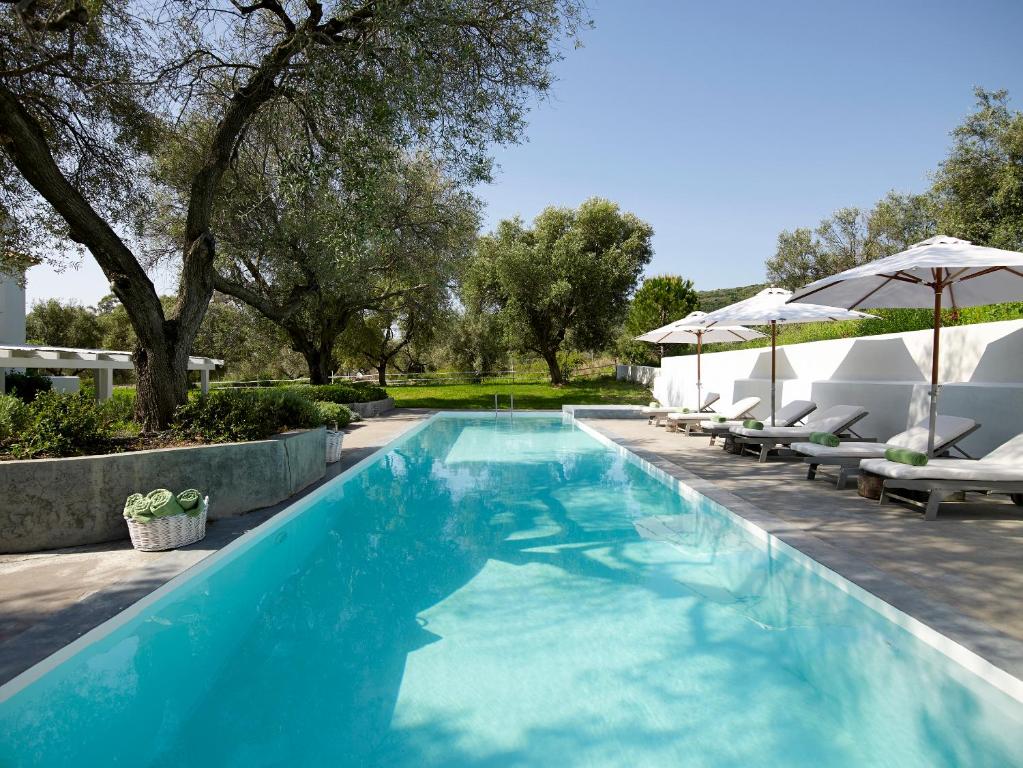 a swimming pool with lounge chairs and umbrellas at Olivemare in Katelios