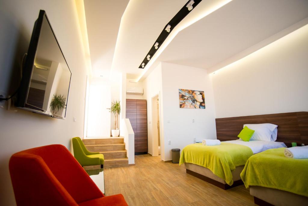 a hotel room with two beds and a chair at Garni Hotel Apel Apartments in Niš