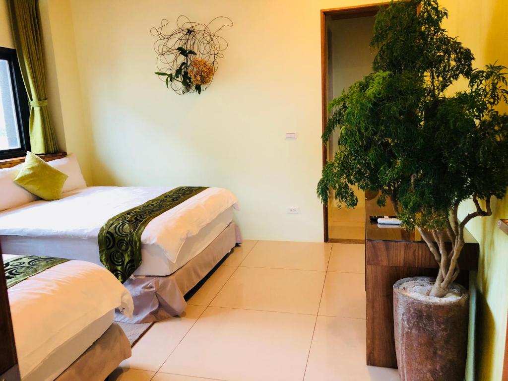 a room with two beds and a potted tree at Weiden House in Luodong