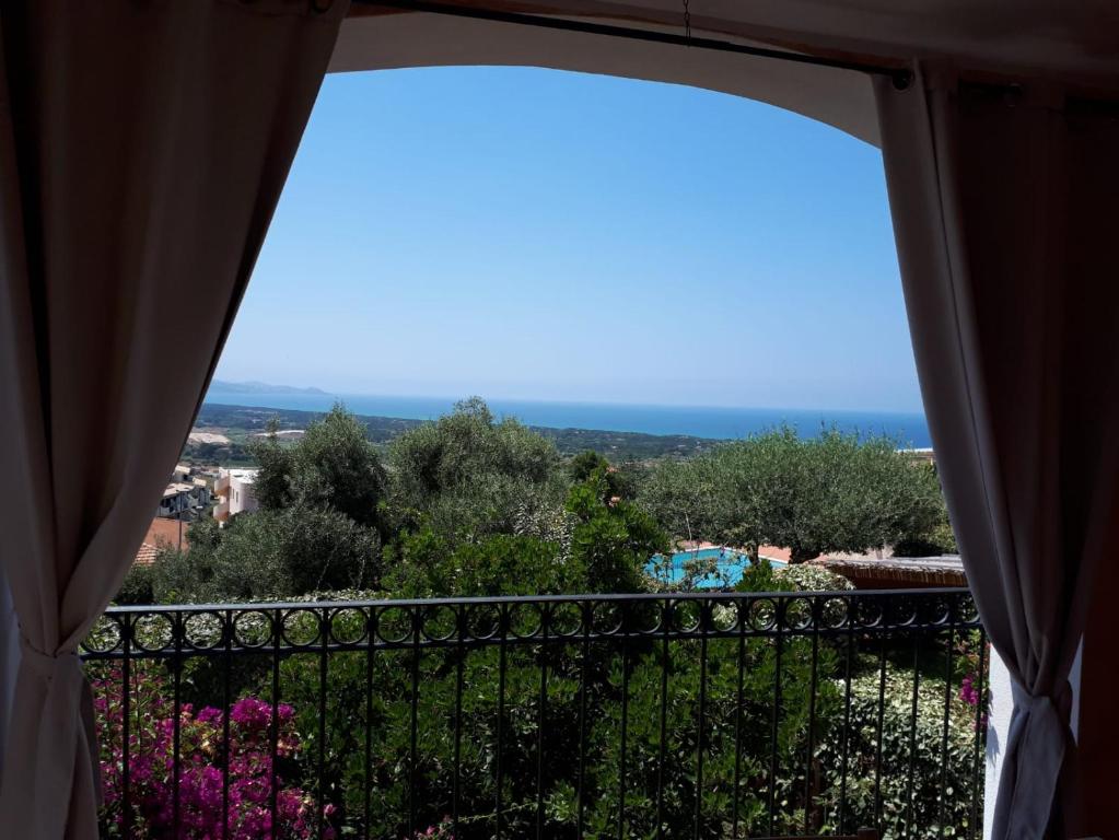 a view out a window of a balcony with flowers at Villa La Minda with a stunning view in Badesi