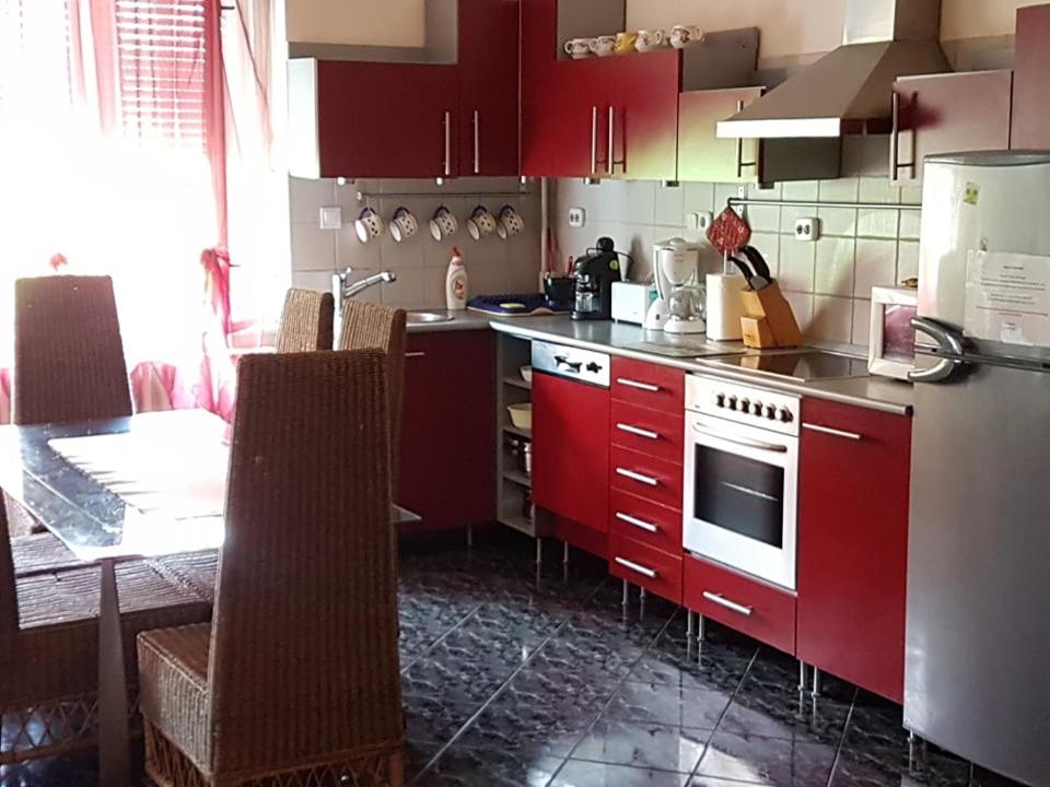 uma cozinha com armários vermelhos e uma mesa com mesa; em Szőke Tisza Vendégház em Szajol
