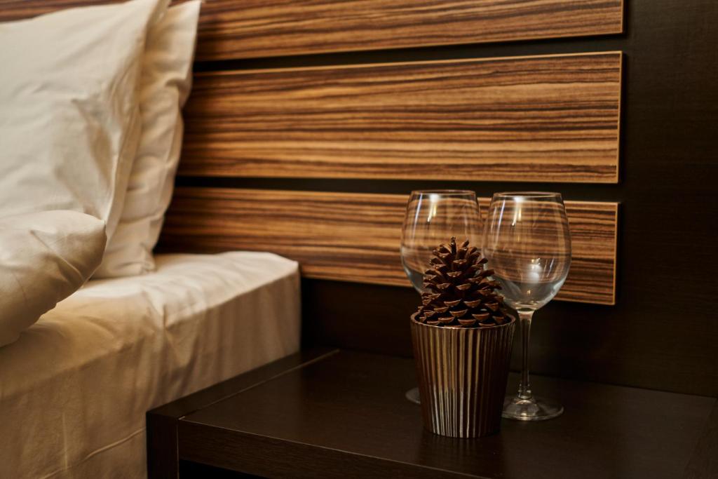 two wine glasses on a table next to a bed at studio ATLANTIC in Pamporovo