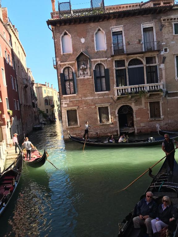 a group of people in gondolas in a canal at Luxury Venetian Rooms in Venice