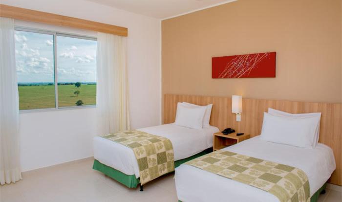 a hotel room with two beds and a window at Prime Hotel in Rio Verde