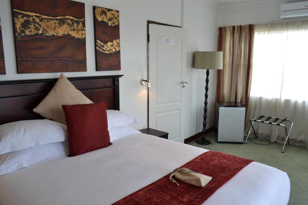 a hotel room with a bed with a purse on it at City Stay in Maseru