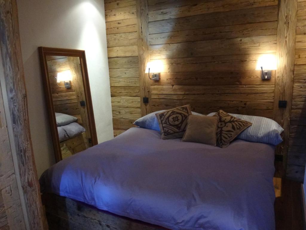 a bedroom with a bed with a wooden wall at La Petite Suite in Megève