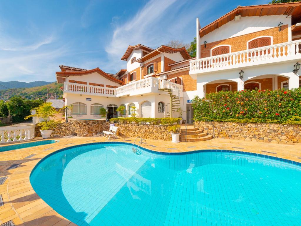 uma villa com piscina em frente a uma casa em Hotel Guanumbis em Ilhabela