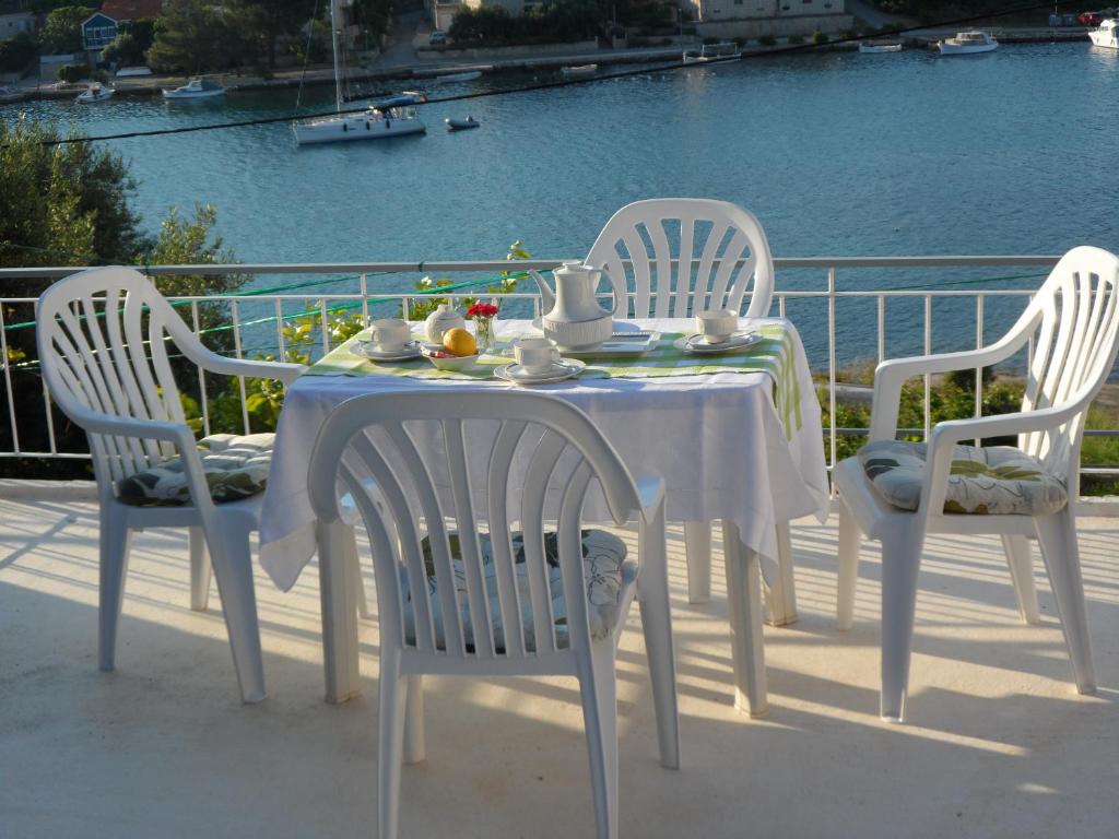 - une table et des chaises blanches avec une table et des boissons dans l'établissement Adrian's Apartments & Winery, à Lumbarda