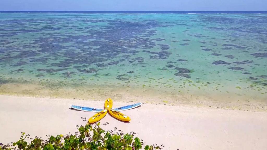 a pair ofogie boards on a beach with the water at Etu Moana Boutique Beach Villas - Adults Only in Arutanga