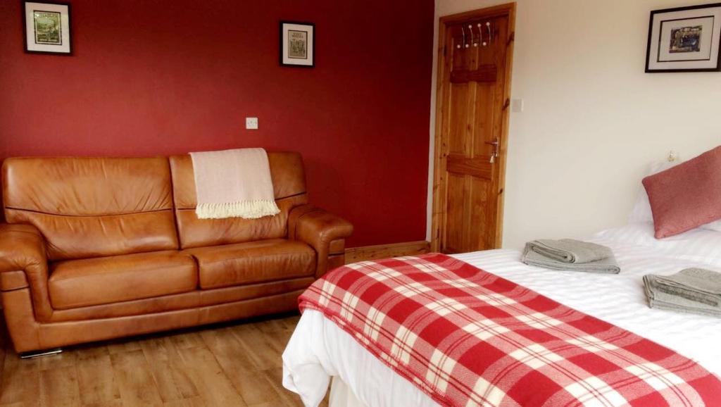 a bedroom with a bed and a leather couch at Maes y Môr in Llanarth