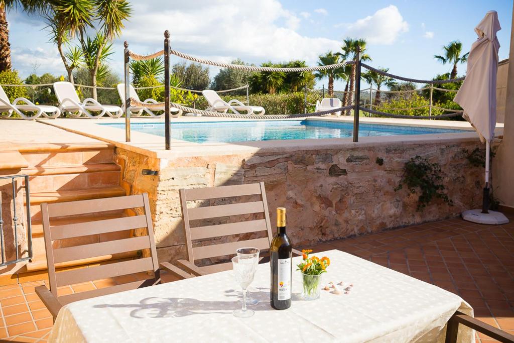 ein Tisch mit einer Flasche Wein und zwei Stühlen neben einem Pool in der Unterkunft Es moli de na Sebastiana in Ses Salines