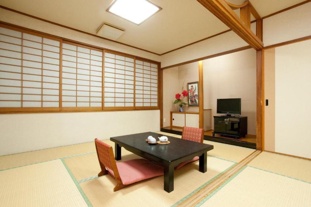 a room with a table and chairs and a television at Okinawa Hotel in Naha