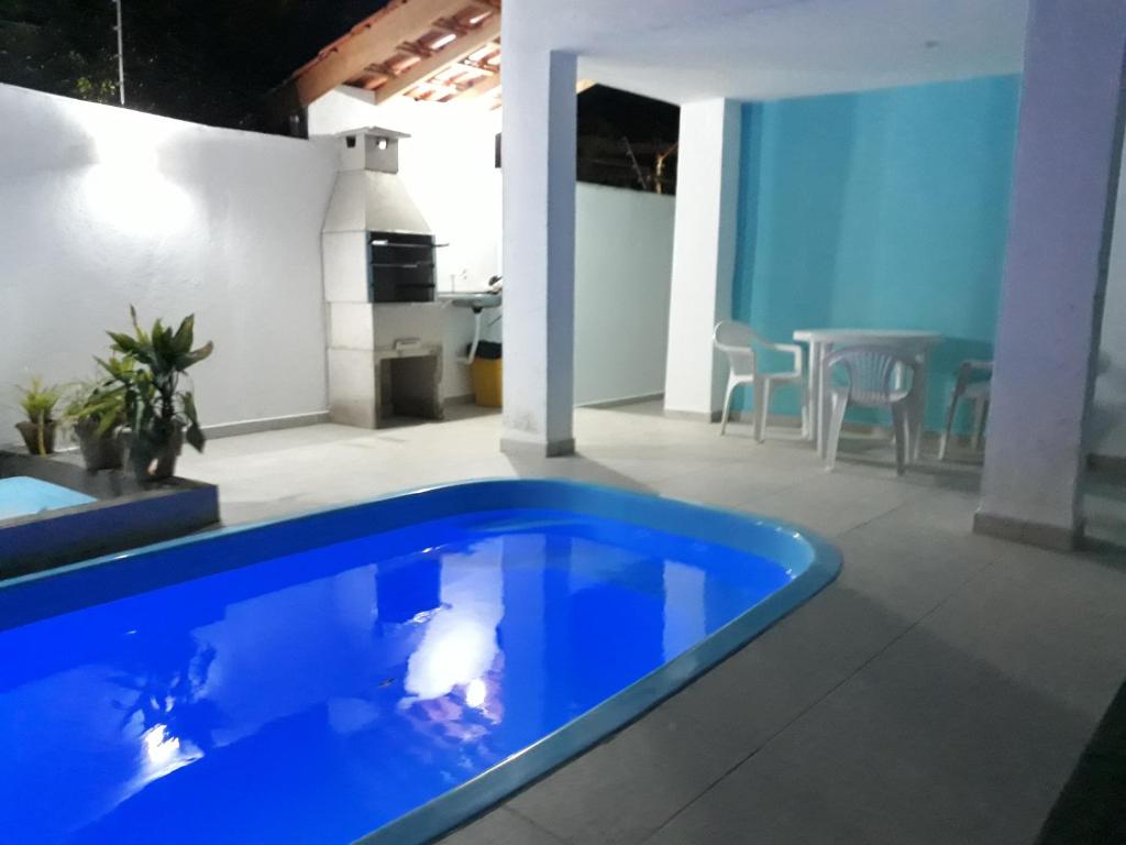 a large blue swimming pool in a room with a table at Sunny apartamentos de 1 e 2 dormitórios na Martin de Sá próximo a praia in Caraguatatuba