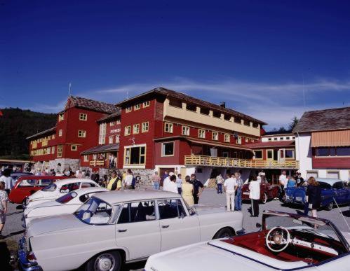 um grupo de carros estacionados em frente a um edifício vermelho em Fossli Hotel em Eidfjord