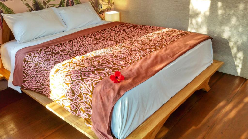 uma cama com uma flor vermelha em cima em Petit Tree em Seminyak