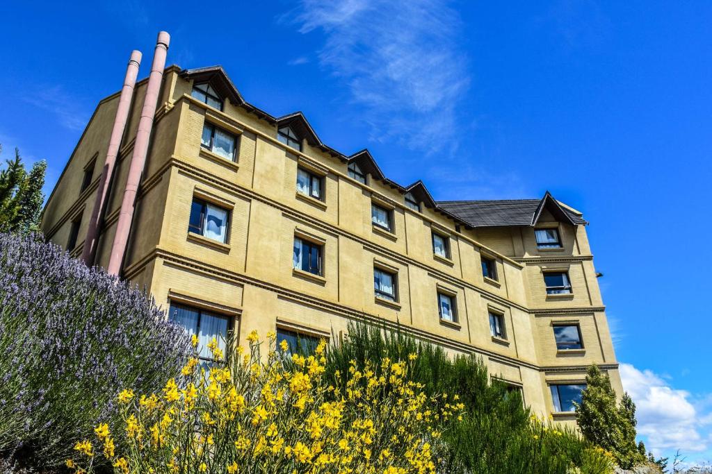 a tall building with windows and yellow flowers at Esplendor by Wyndham El Calafate in El Calafate