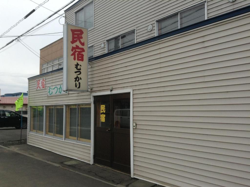 a building with a sign on the side of it at Minshuku Mutsukari in Furano