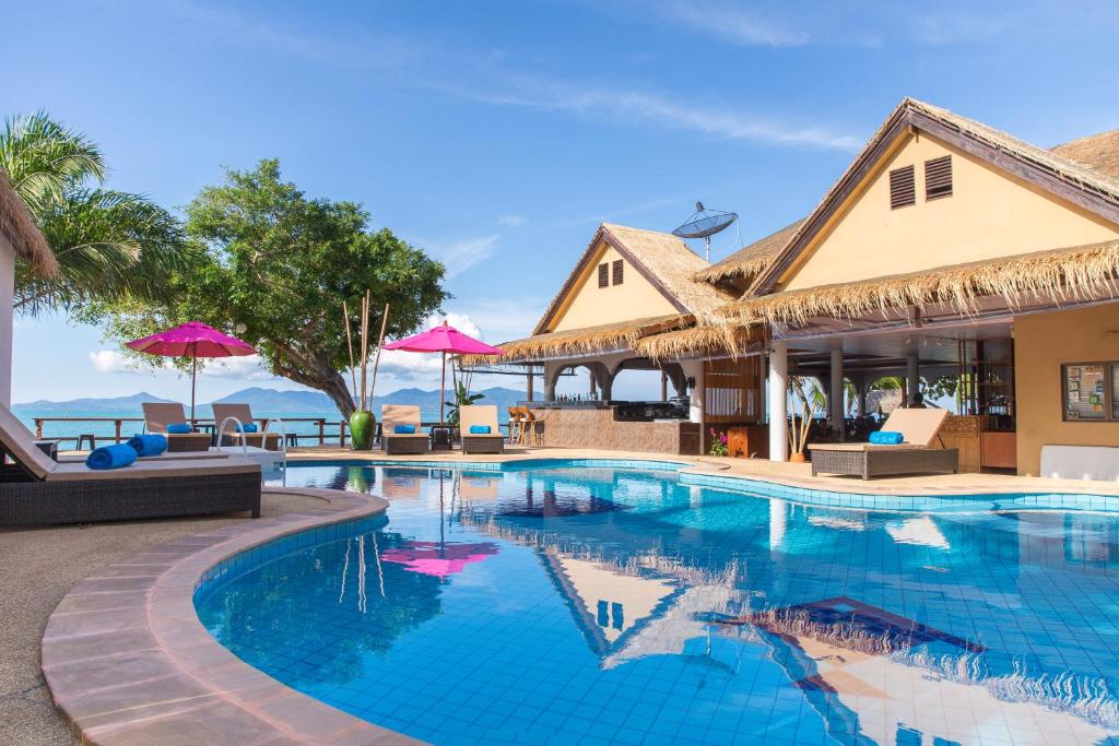 uma piscina num resort com cadeiras e guarda-sóis em Adarin Beach Resort em Mae Nam