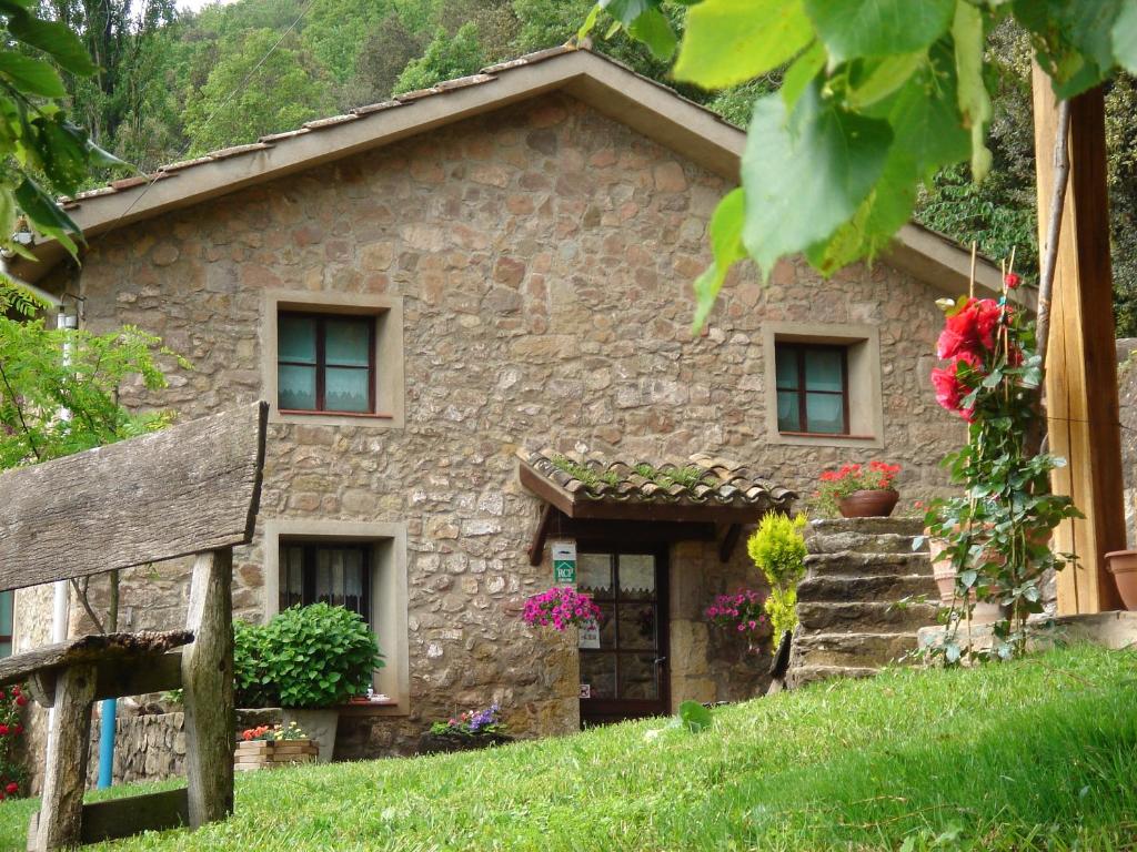 a stone house with flowers in front of it at Mas El Bosquet in Joanetes