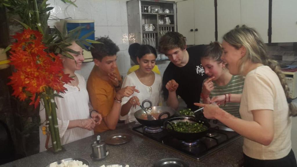 un grupo de personas de pie en una cocina preparando comida en Grace Home en Nueva Delhi