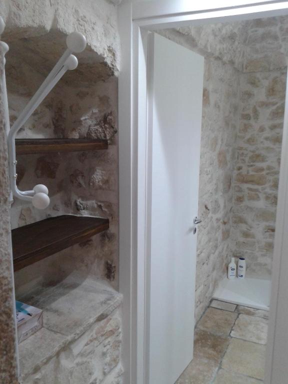 łazienka z kabiną prysznicową obok kamiennej ściany w obiekcie Lilla B&B w mieście Molfetta
