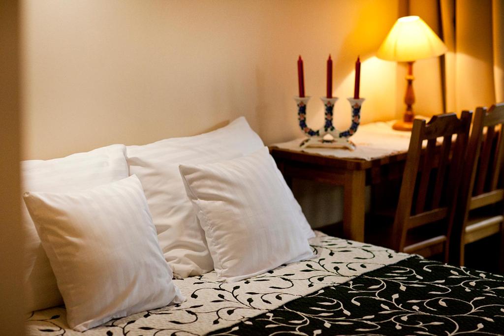 Habitación con cama con almohadas blancas y mesa. en Apartamenty Argo, en Cracovia