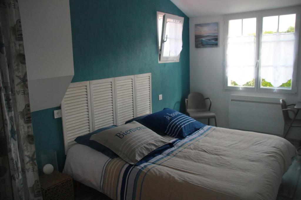 Un dormitorio con una cama con una pared azul. en KARABI, en Barbâtre
