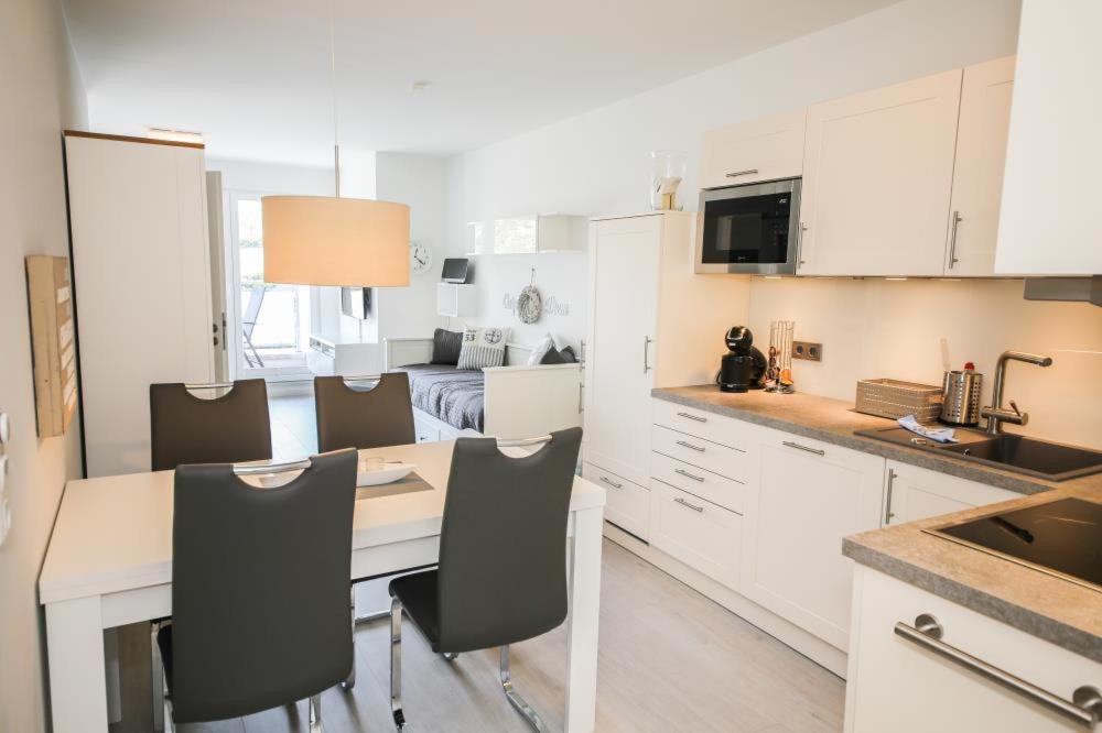 シャルボイツにあるFerienwohnung Sunshine Beachhouse 111の白いキャビネット、テーブルと椅子付きのキッチンが備わります。