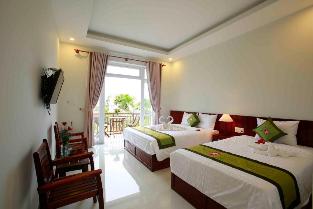 a hotel room with two beds and a balcony at La Uy Villa in Hoi An