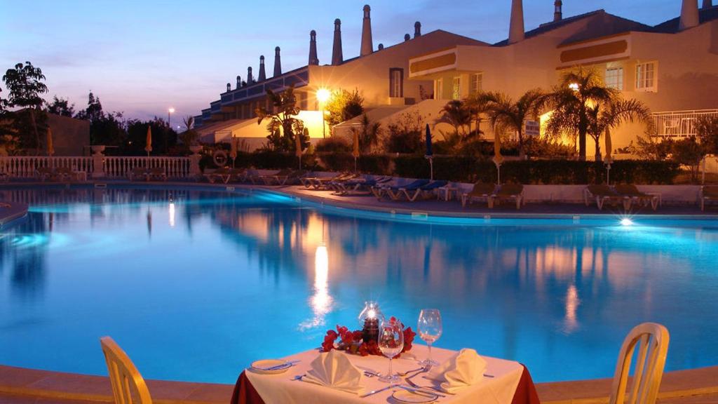 アルブフェイラにあるmagnifique maison en resort près des plagesのスイミングプールの横にテーブルとワイングラス
