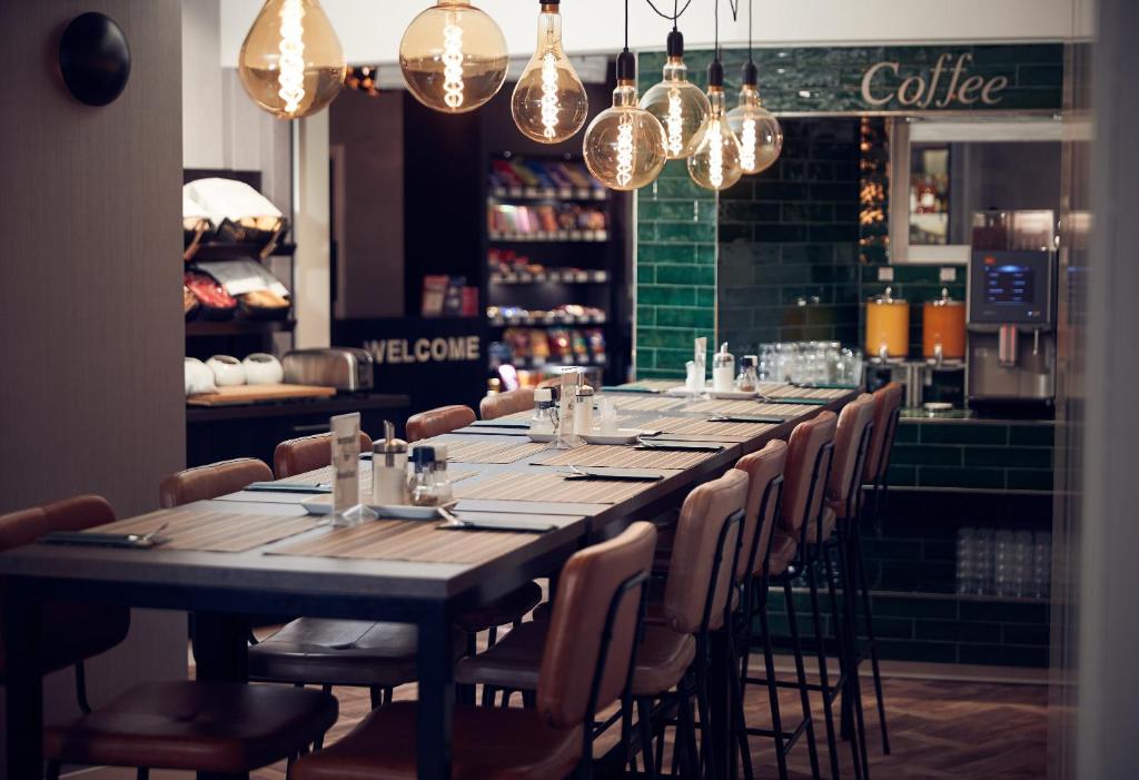 a long table in a restaurant with chairs and lights at Singel Hotel Amsterdam in Amsterdam