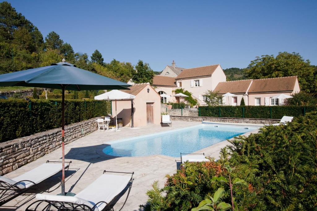a swimming pool with two chairs and an umbrella at Domaine De La Combotte in Nantoux