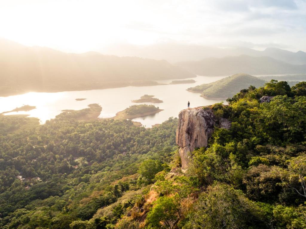 a person standing on top of a cliff overlooking a lake at The Pepper Cottage in Gomagoda