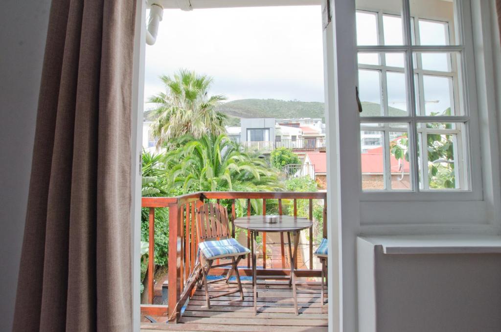 balcón con mesa, sillas y ventana en Villa Costa Rose - No Loadshedding en Ciudad del Cabo