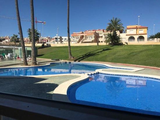 une grande piscine bordée de palmiers et un bâtiment dans l'établissement Mazarron Beach apartment, à Mazarrón