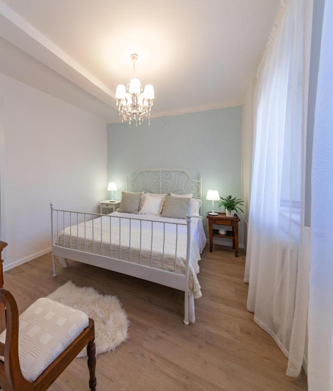 a white bedroom with a bed and a chandelier at il risveglio di alice in Fano