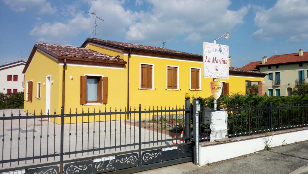 a yellow house with a fence in front of it at B&B Martina in Agugliaro