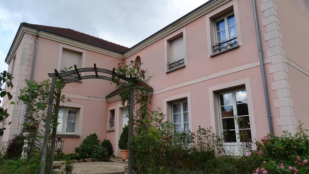 uma casa cor-de-rosa com um arco à frente. em la maison du saussoy em Saint-Augustin