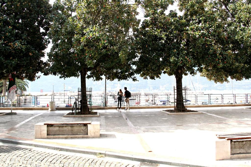 two people standing under trees in a parking lot at Apartments Astoria HN in Herceg-Novi