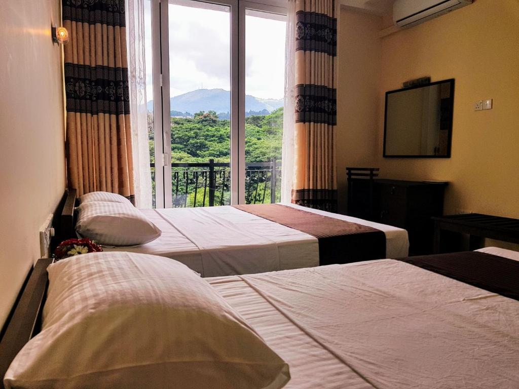 a hotel room with two beds and a large window at Hanthana Mount View in Kandy