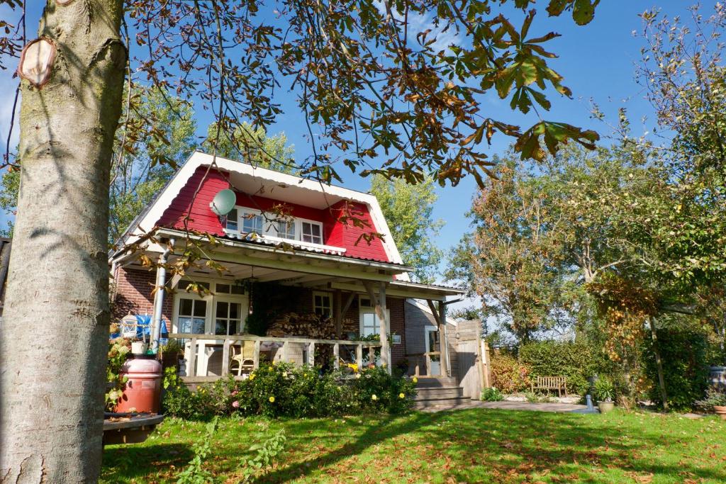 una casa antigua con techo rojo y un árbol en Bed & Breakfast "Bij Lucie", en Wijtgaard