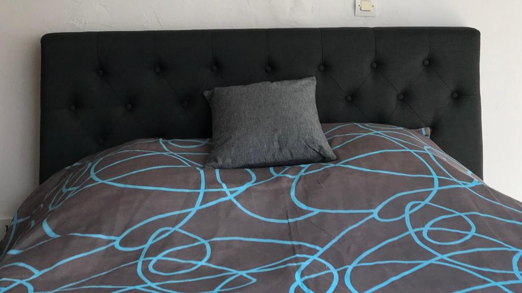 a bed with a black headboard and a gray pillow at Lumineux T2 Vieille ville 3 pers parking gratuit - by La Source d&#39;OrFée in Boulogne-sur-Mer