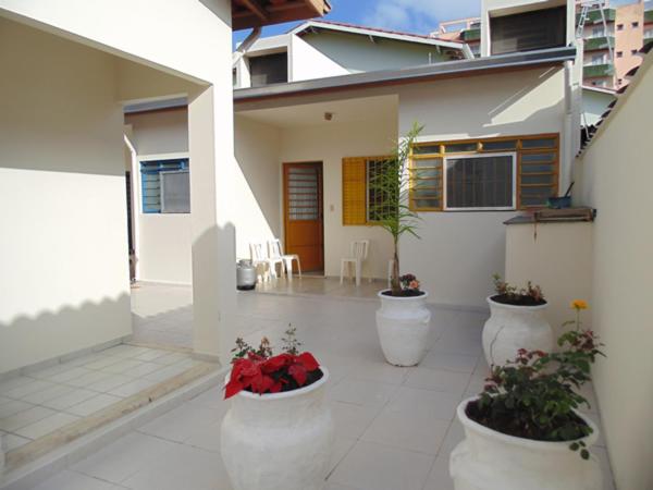 een binnenplaats van een huis met drie witte potten met bloemen bij Sunny Chalés na prainha do jacaré muito próximo in Caraguatatuba