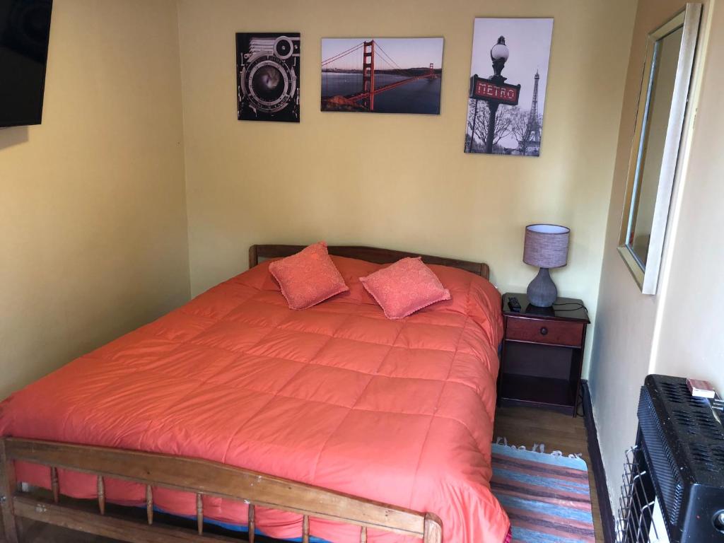 1 dormitorio con 1 cama con edredón de naranja en Hostal Radal Molina, en Molina