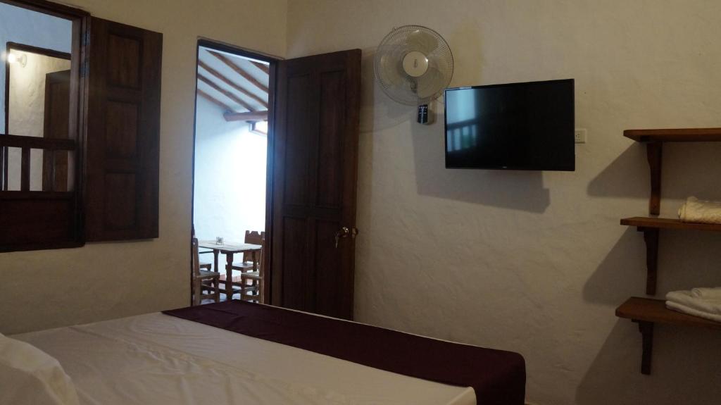 a bedroom with a bed and a flat screen tv at MONCOGUA Casa de Hospedaje in Barichara